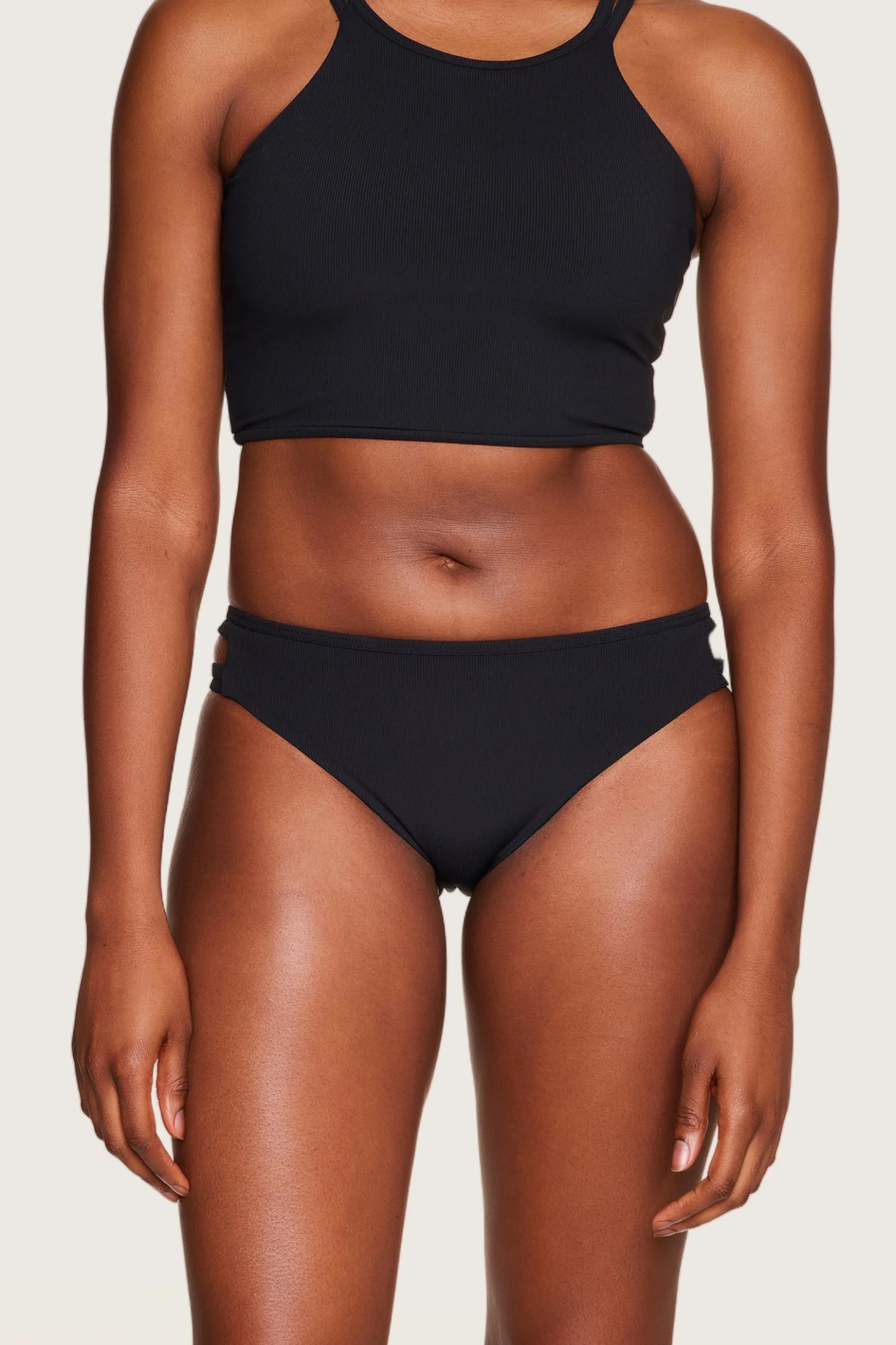 Person trägt schwarzen MYMARINI Bikini mit hochgeschlossenem Top und Bikinihose in Mid rise.#color_black