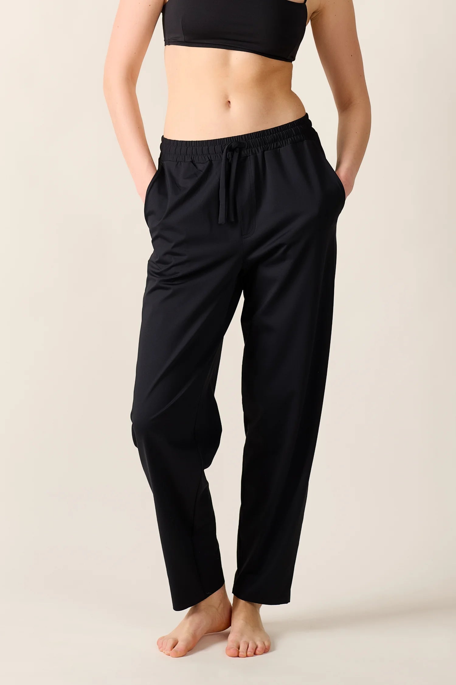 Person trägt schwarze MYMARINI-Hose mit elastischem Bund und seitlichen Taschen, kombiniert mit einem schwarzen Top.#color_black