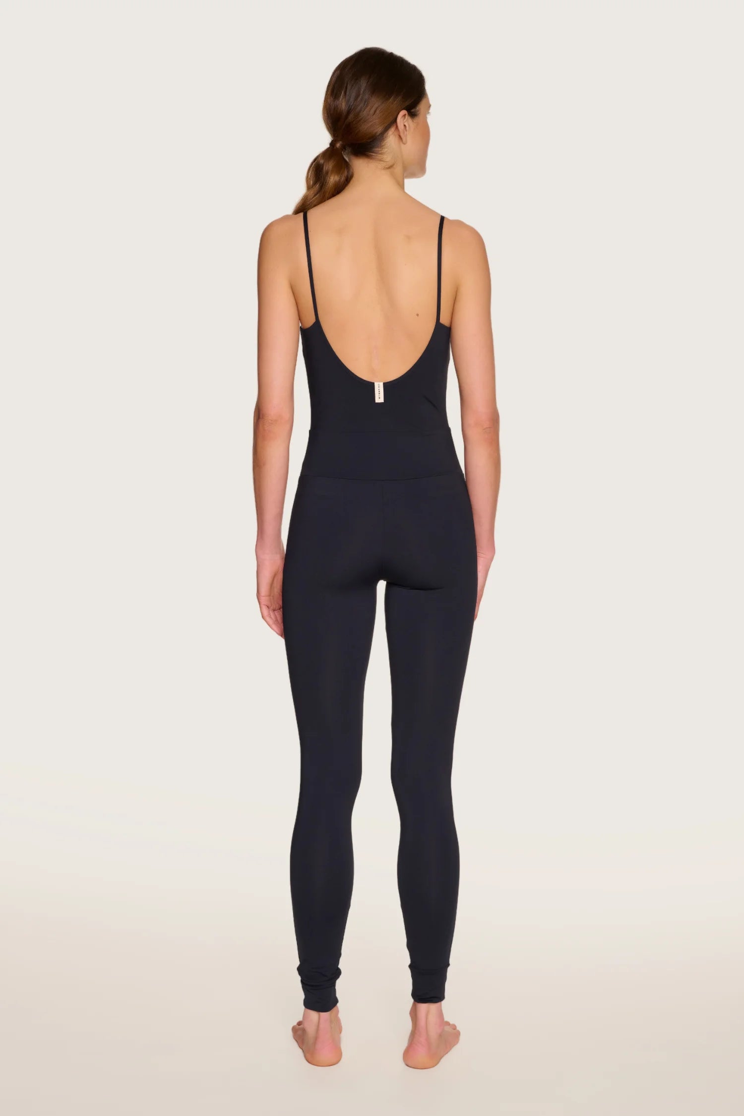 Person von hinten in einem schwarzen MYMARINI-Overall mit tiefem Rückenausschnitt und Spaghettiträgern.#color_black