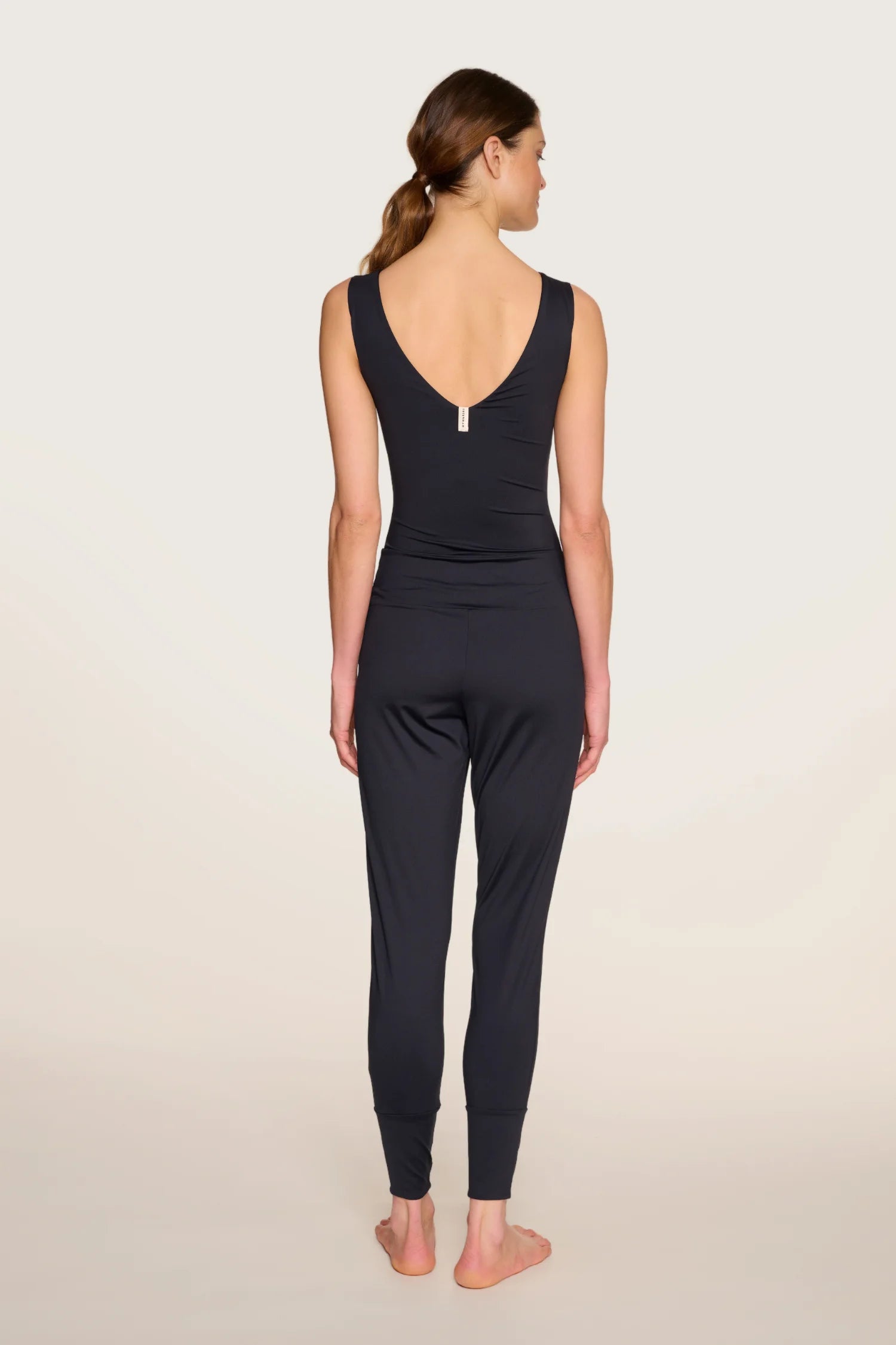 Person von hinten in schwarzem MYMARINI-Overall mit V-Ausschnitt und breiten Trägern.#color_black