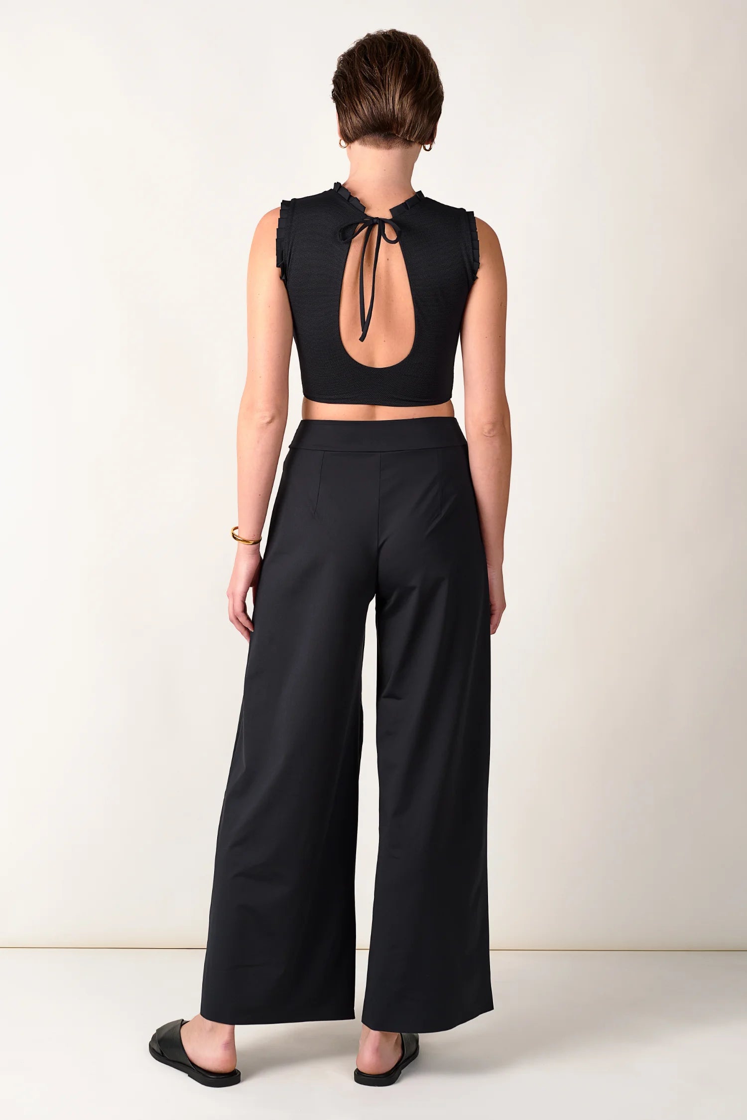 Rückansicht einer Person in schwarzem MYMARINI-Top mit tiefem Rückenausschnitt und schwarzer Hose.#color_black