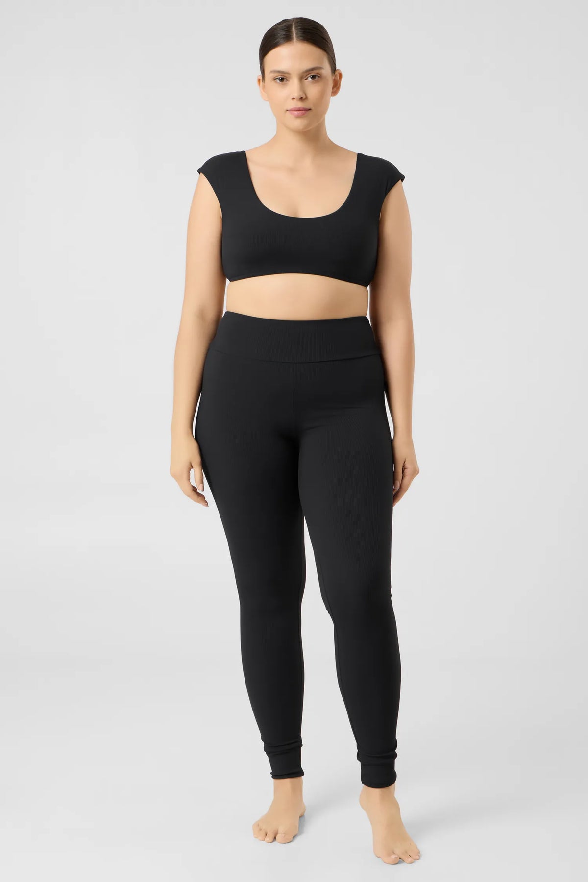 Woman in the black MYMARINI SHOULDER TOP bikini top with wide straps and black leggings, front view#color_black-ribbed