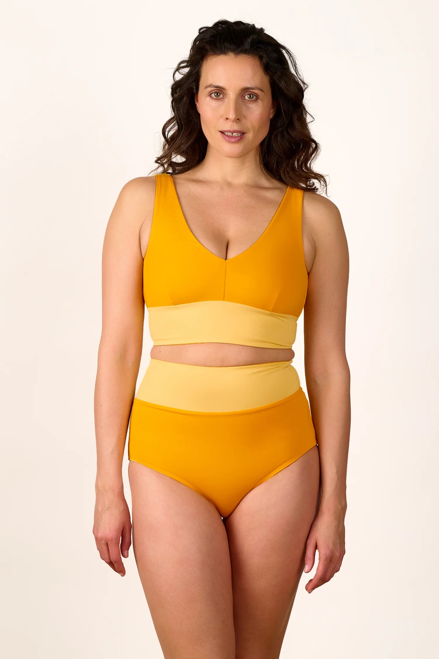 Frau trägt MYMARINI Bikini mit V-Ausschnitt und High Waist in Gelb.#color_buttermilk-soleil