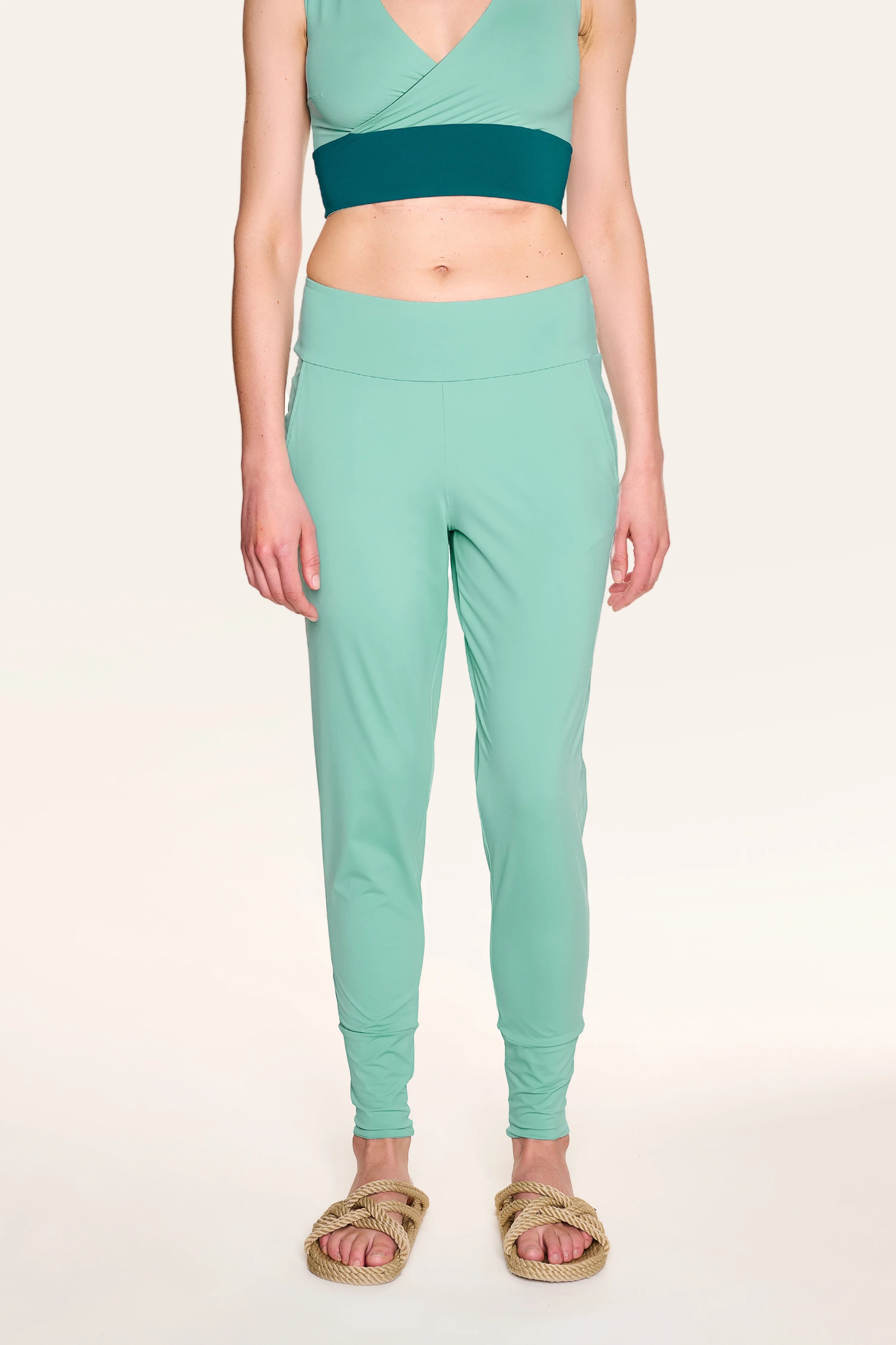 Person trägt MYMARINI-Top mit V-Ausschnitt und Hose in Mintgrün, dazu Sandalen.#color_eucalyptus