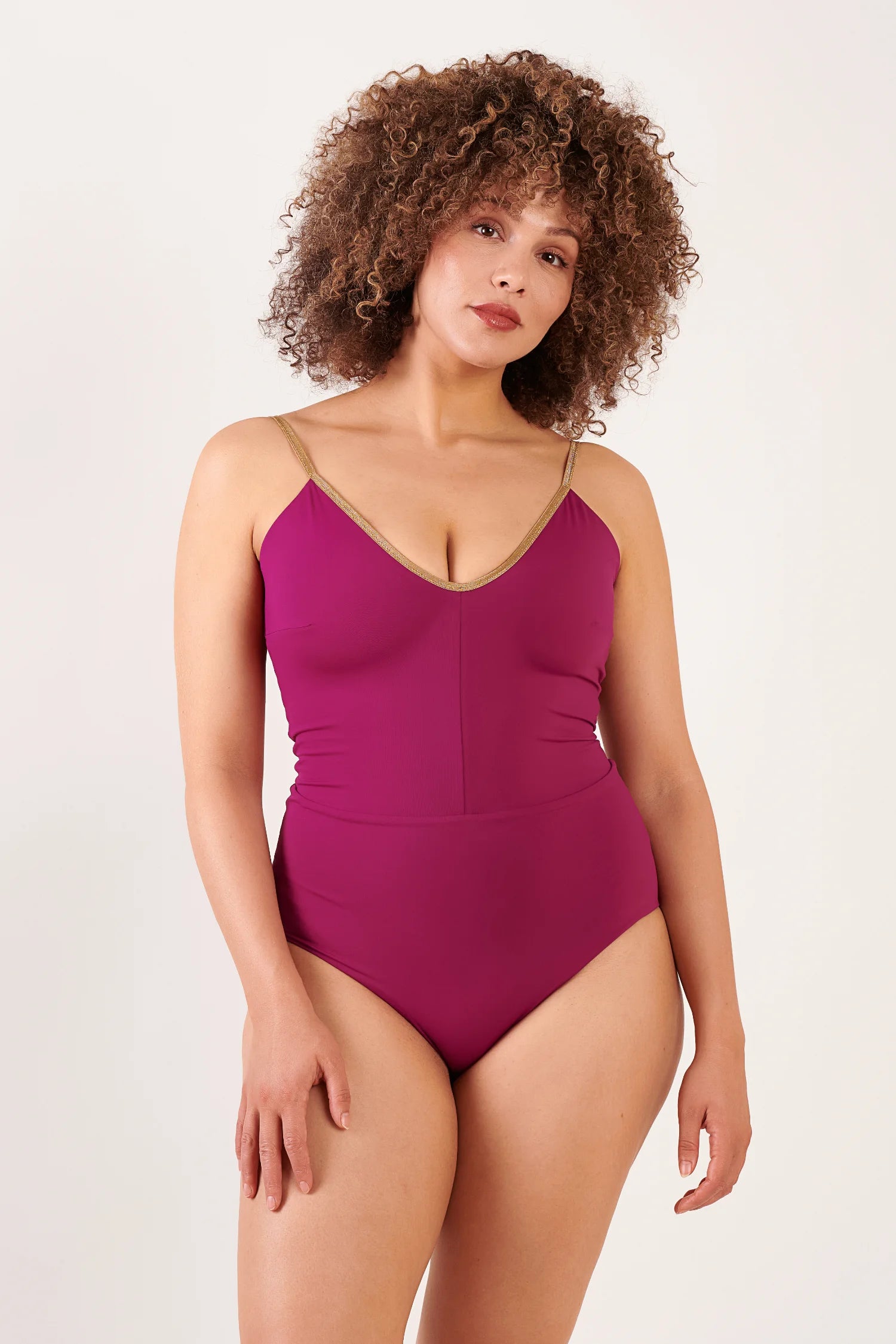 MYMARINI One-Piece-Badeanzug in Magenta mit goldenen Spaghettiträgern und V-Ausschnitt, von einer Frau getragen.#color_maroon-hortensia