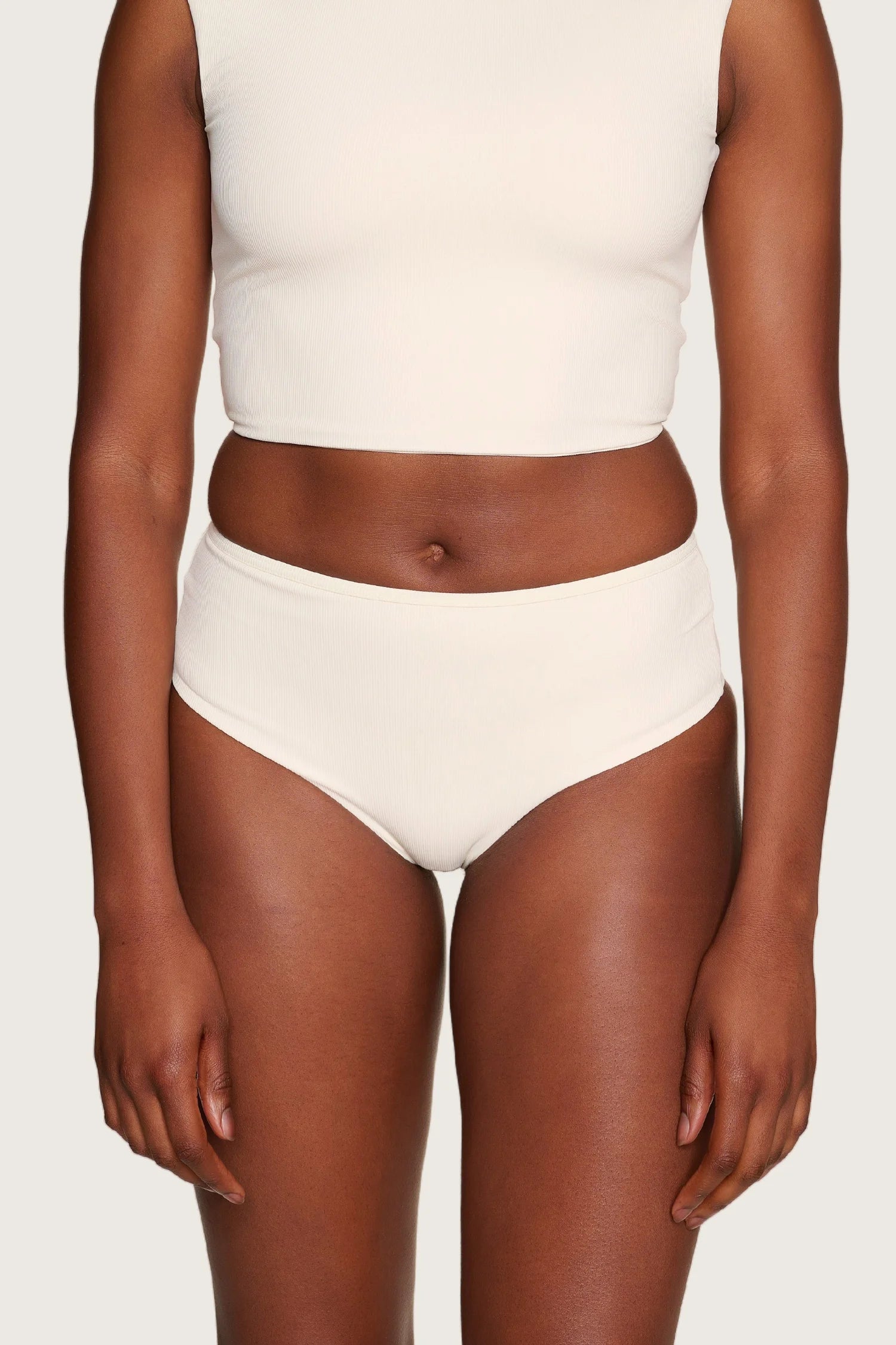 Person trägt MYMARINI Bikinihose in Creme mit hohem Beinausschnitt und passendem Top.#color_off-white