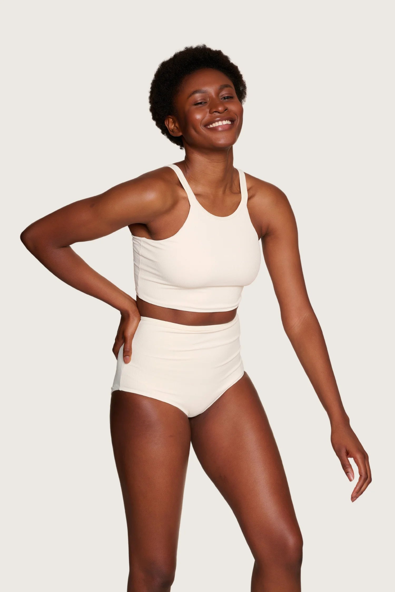 Lächelnde Person trägt MYMARINI Bikini mit breiten Trägern und High Waist Schnitt vor neutralem Hintergrund.#color_off-white