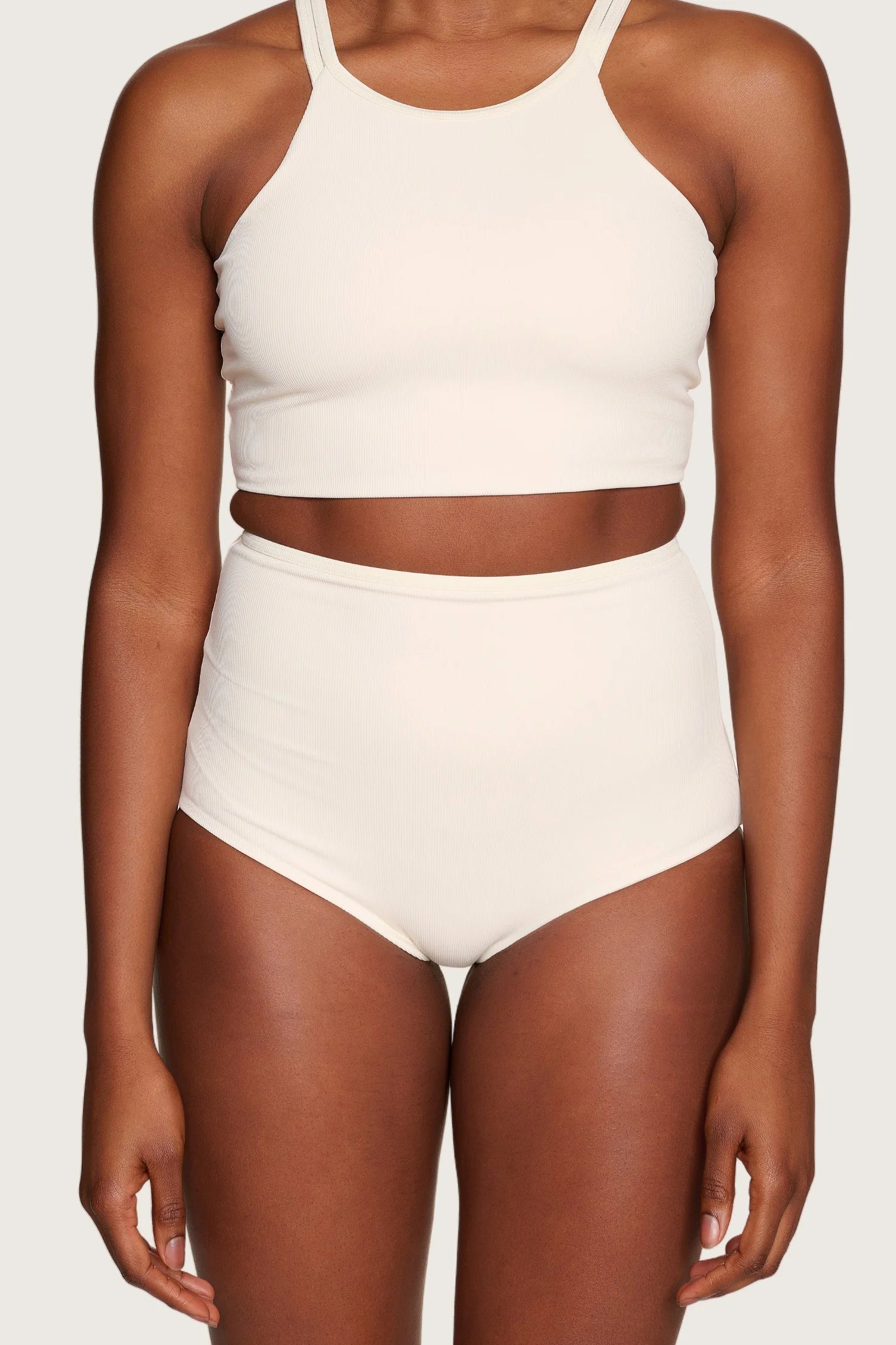 Person trägt MYMARINI Bikinitop mit breiten Trägern und hoch geschnittene Bikinihose in Creme.#color_off-white