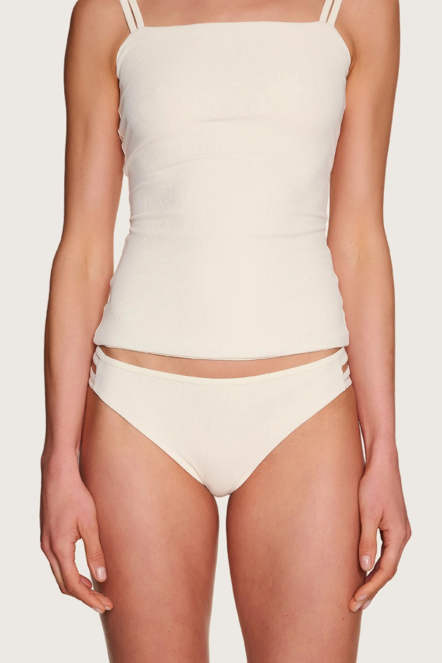 Person trägt MYMARINI Bikinitop mit Spaghettiträgern und Bikinihose, beide in Cremeweiß.#color_off-white