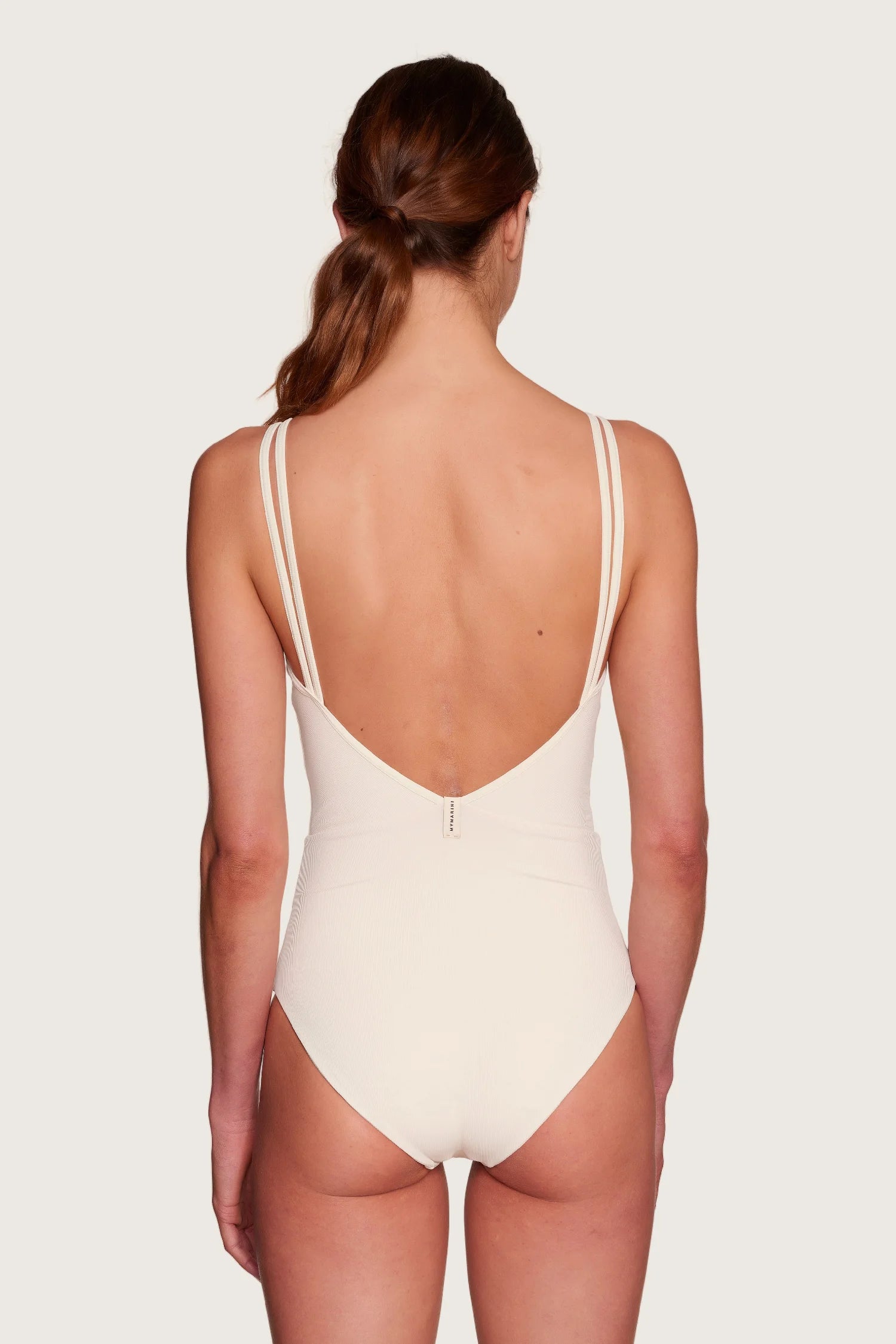 Rückansicht eines MYMARINI One-Piece mit tiefem Rückenausschnitt und Spaghettiträgern in Cremeweiß.#color_off-white